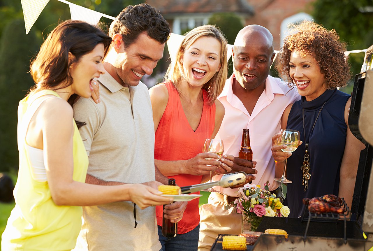 mature friends enjoying outdoor summer barbeque in garden